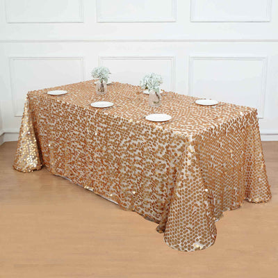 Gold sequin tablecloth draping a table with plates and flowers.