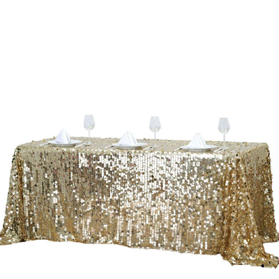 Gold sequin tablecloth on a table with wine glasses and napkins