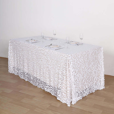 White sequin tablecloth draped over a long table with dinnerware and glasses.