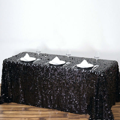Black sequin tablecloth draped elegantly over a table with dinnerware set.