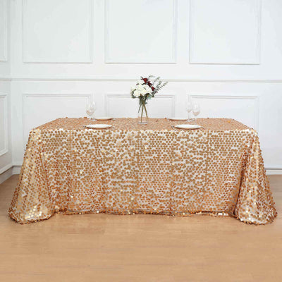 Gold sequin tablecloth on a styled dining table with floral centerpiece.