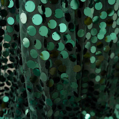Green sequin fabric with circular embellishments for fashion and decor.