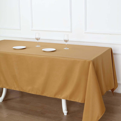 Elegant gold tablecloth draped over a table with plates and wine glasses.