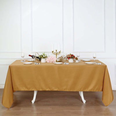 Elegant gold tablecloth draped over a dining table set with dishes and decor.