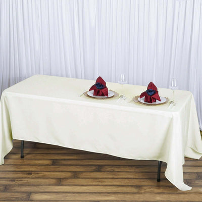 Elegant cream tablecloth with decorative plates and napkins on a wooden floor.