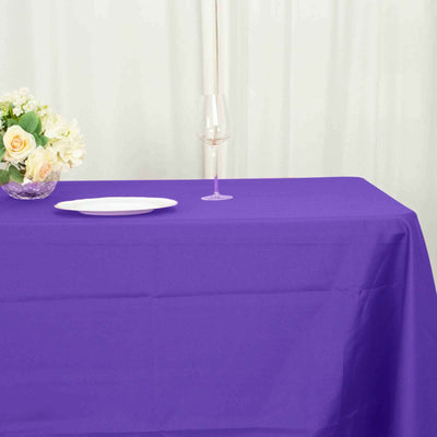 Purple tablecloth draped elegantly on a table with a plate and floral arrangement.