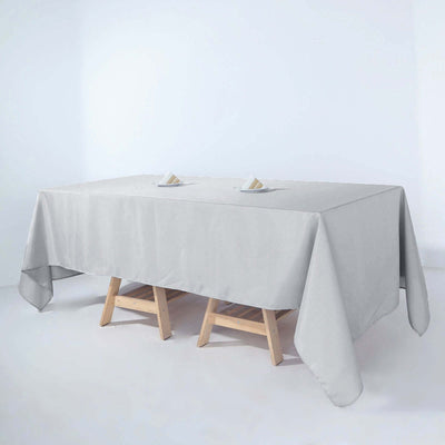 Gray tablecloth draped over a wooden table with napkins on top