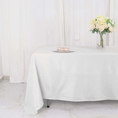 Elegant white tablecloth on a dining table with floral centerpiece and wine glass.