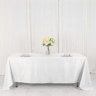 Elegant white table setup with floral centerpiece and dinnerware.