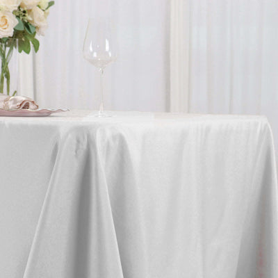 White satin tablecloth draped elegantly on a table with a wine glass.