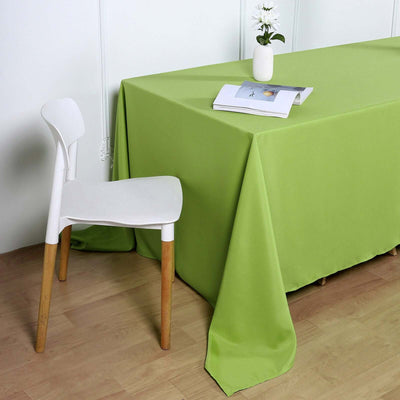 Green tablecloth draping a table with a white chair and vase on top.