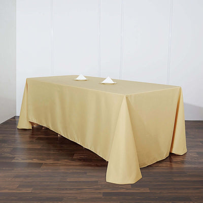 Beige tablecloth draped over a rectangular table with folded napkins.