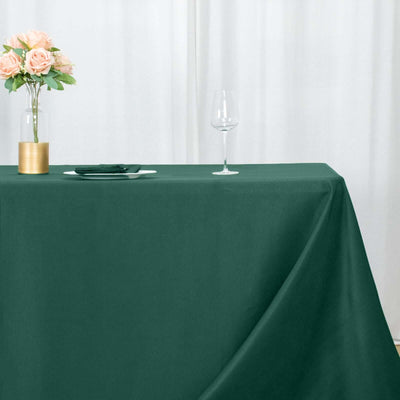 Green tablecloth draped elegantly on a table with a vase and glass
