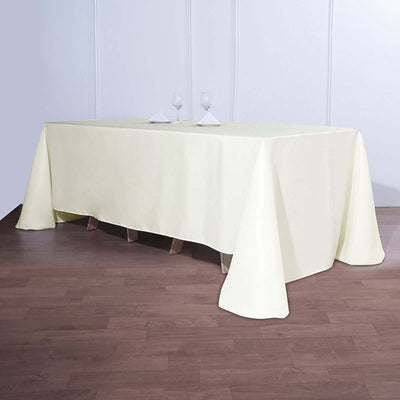Cream tablecloth draped over a table with glasses and napkins.