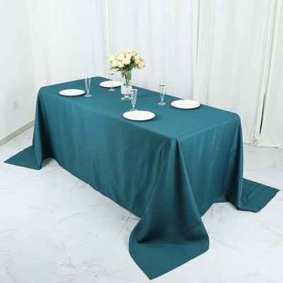 Elegant teal tablecloth draped over a dining table with floral centerpiece.