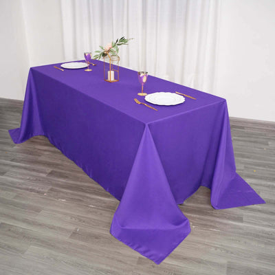 Purple tablecloth draped over a table set for dining with plates and glassware.