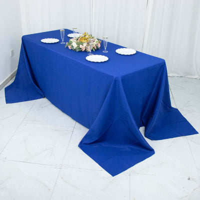 Blue tablecloth draped elegantly over a table set with plates and floral centerpiece.