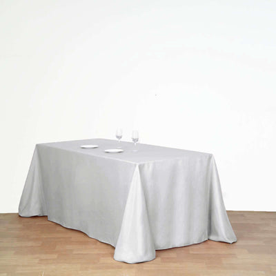 Grey tablecloth draped over a table with plates and glasses