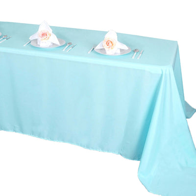 Light blue tablecloth draped on a table set for dining with plates and napkins.