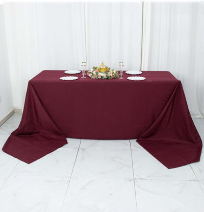 Burgundy tablecloth draped over a rectangular table with decorative centerpieces.