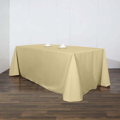 Beige tablecloth draped over a table with folded napkins on top.