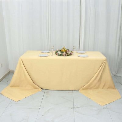 Elegant yellow tablecloth on a table set for dining with floral centerpiece.