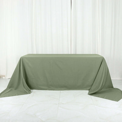 Olive green tablecloth draped over a table on a plain backdrop.