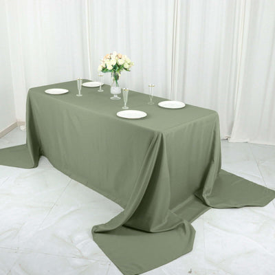 Olive green tablecloth draped over a table with plates and glasses.