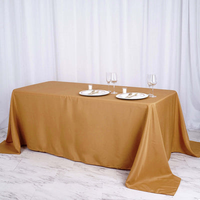 Elegant gold tablecloth with plates and glasses set for dining.