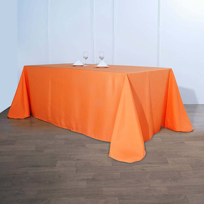 Orange tablecloth draped over a table with wine glasses on top.
