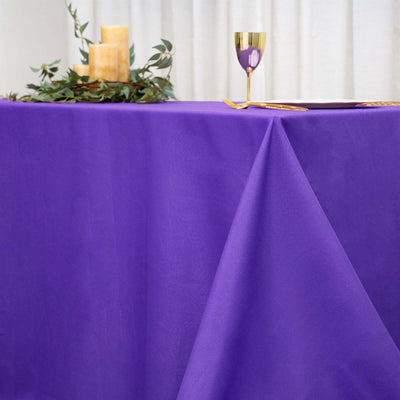 Purple tablecloth draped elegantly on a table with candles and a golden cup.