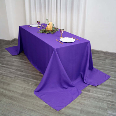 Purple tablecloth draped elegantly on a table setting with candles and dinnerware.
