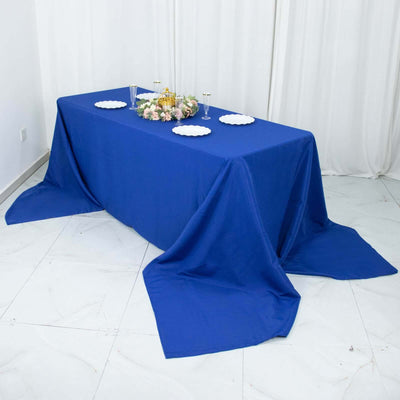 Blue tablecloth draped over a table with decorative plates and floral centerpiece.