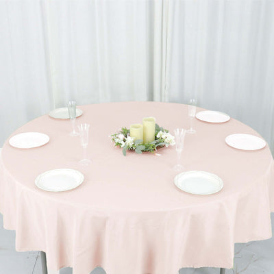 Elegant round table set with plates and candles, adorned with floral centerpiece.