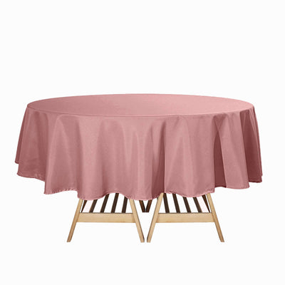 Round pink tablecloth draped over a wooden table.
