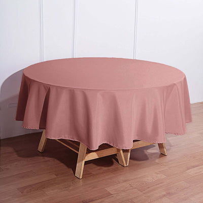 Round pink tablecloth draped over a wooden table in a home setting.