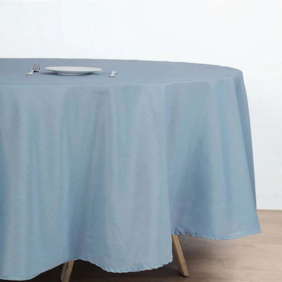 Round blue tablecloth on a wooden table with a plate and cutlery.