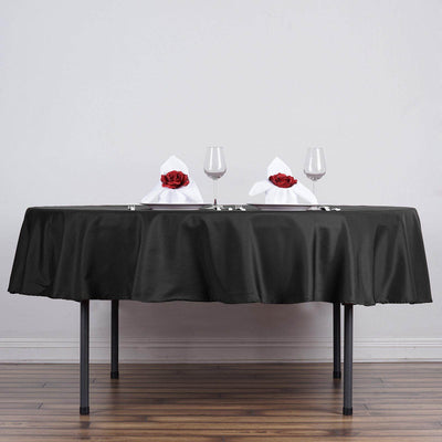 Elegant dining table set with black tablecloth, wine glasses, and rose-adorned napkins.