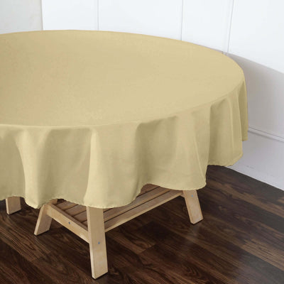 Round beige tablecloth draped over a wooden table.