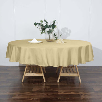 Round yellow tablecloth on wooden table with vase and flowers