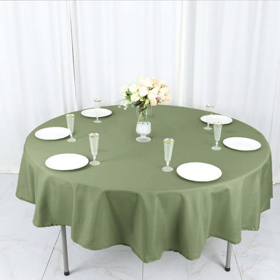 Round olive green tablecloth on a dining table set for a meal.