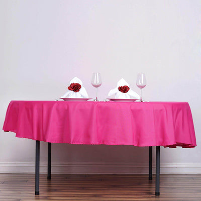 Pink tablecloth draped on a table set for two with elegant napkins and wine glasses.