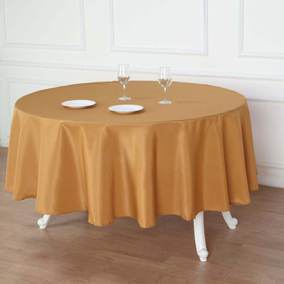 Round gold tablecloth draped over a table with plates and glasses.