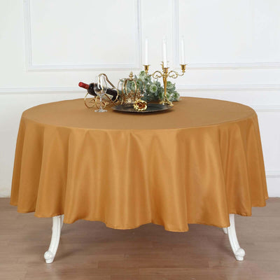Elegant gold tablecloth draped on a round table with a decorative centerpiece.