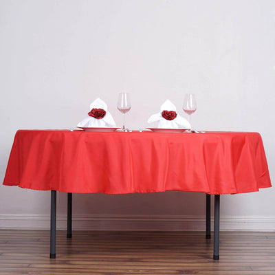 Red tablecloth set with white napkins and glasses for a dining setting.