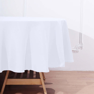 White tablecloth draping over a wooden table in a minimalistic setting.