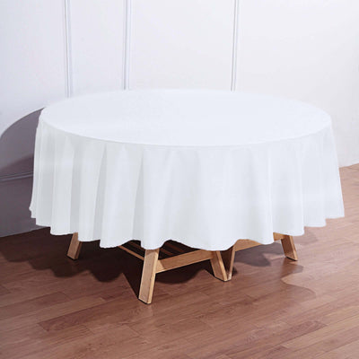 White round tablecloth draped over a wooden table in a bright setting.