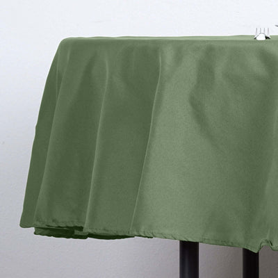 Green tablecloth draped over a round table in a studio setting.
