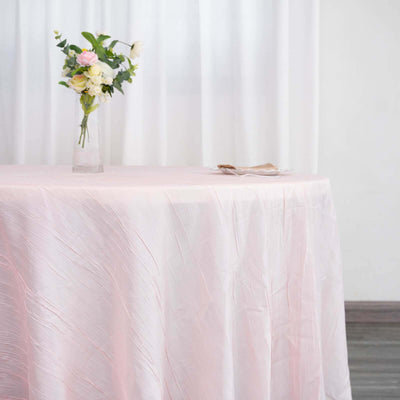Pink tablecloth draped over a table with a vase of flowers on top.