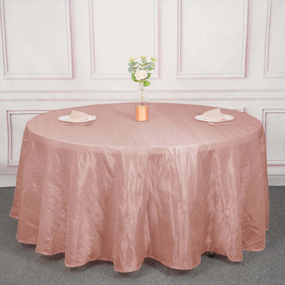 Round blush tablecloth draped over a table with floral centerpiece and plates.
